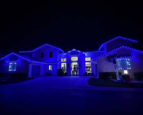 Night view of a home outlined in blue Christmas roofline lights