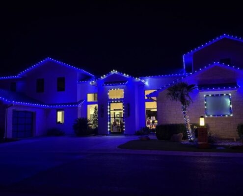 Blue LED roofline Christmas lights and outlined windows on a two-story home