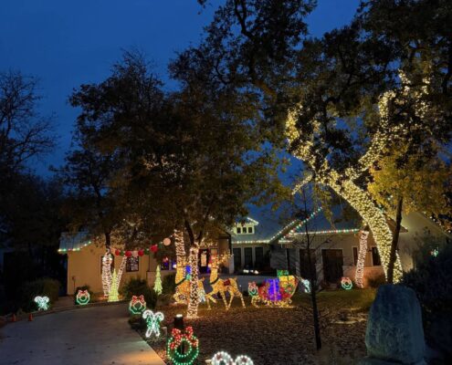 Candy cane yard lights along a driveway with lit trees and a holiday yard display