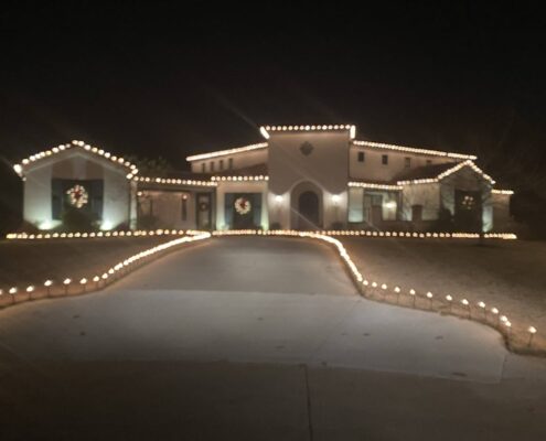 Home with roofline Christmas lights, lit wreaths and a driveway outlined in lights