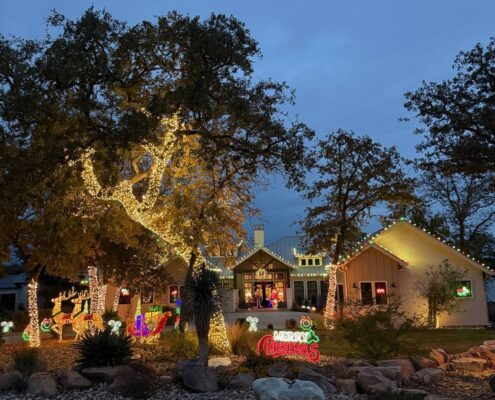 Festive front yard Christmas display with lit oak trees, reindeer and a Merry Christmas sign