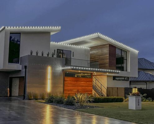 Modern contemporary home with white roofline Christmas lights and a lit tree