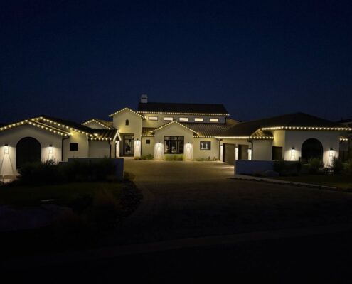 Modern white stucco home with roofline Christmas lights at night