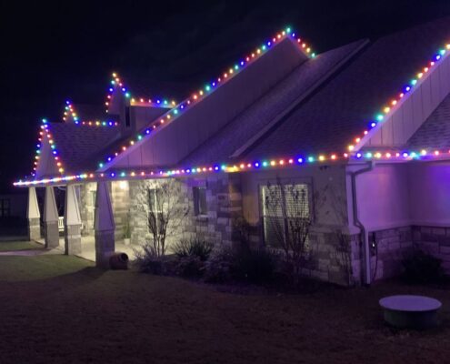 Stone home with multicolor Christmas lights along the roofline
