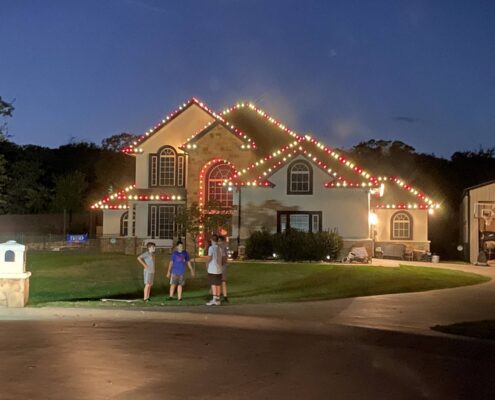 Two-story home outlined in red and white Christmas roofline lights