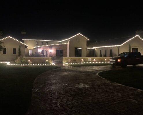 Single-story home with roofline and landscape bed Christmas lights at night