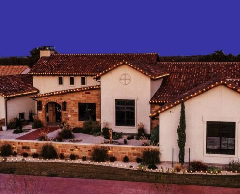 Spanish tile roof home with roofline Christmas lights and lit garden paths